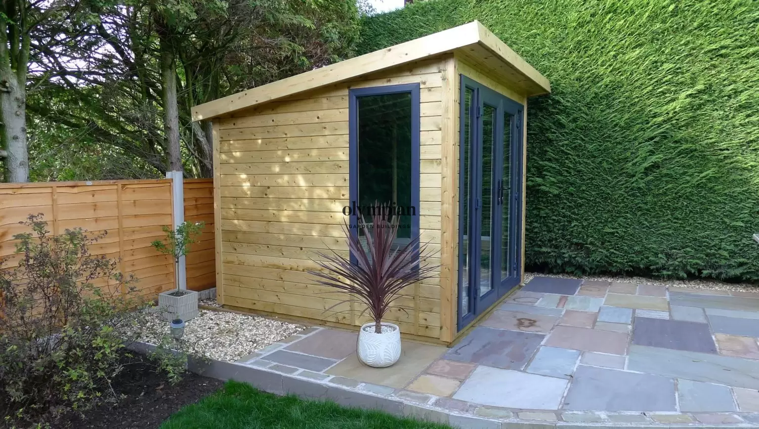 An 8ft x 8ft garden building with single-sloping roof and UPVC doors, in a landscaped garden setting